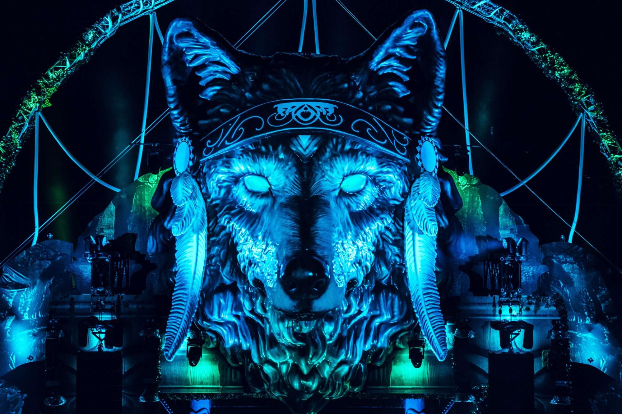 A giant wolf's head on an outdoor stage with blue lighting on it at night